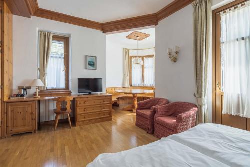 a bedroom with a bed and a desk and a chair at Franceschi Park Hotel in Cortina dʼAmpezzo