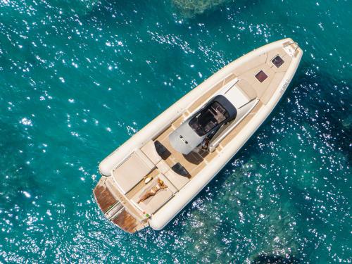a white boat floating in the blue water at Le Calette Bay in Cefalù