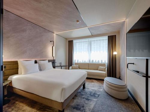 a hotel room with a large white bed and a couch at Novotel München Airport in Freising