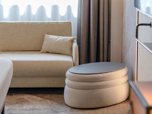 a living room with a chair and a ottoman at Novotel München Airport in Freising