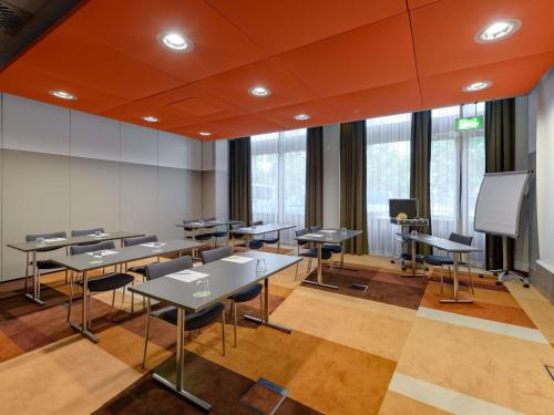 a classroom with tables and chairs and a screen at Novotel München Airport in Freising