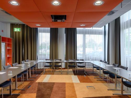 a conference room with tables and chairs and windows at Novotel München Airport in Freising