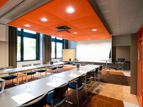 a conference room with tables and chairs and a whiteboard at Novotel München Airport in Freising