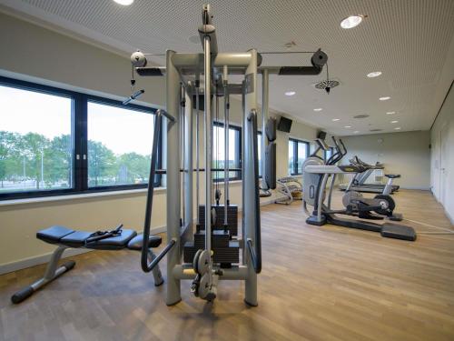 a gym with several treadmills and elliptical machines at Novotel München Airport in Freising