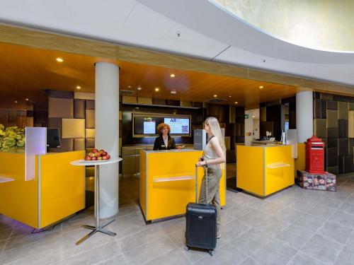 a woman with a suitcase standing in a hotel lobby at Novotel München Airport in Freising