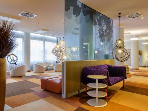 a lobby with a purple couch and a stool at Novotel München Airport in Freising