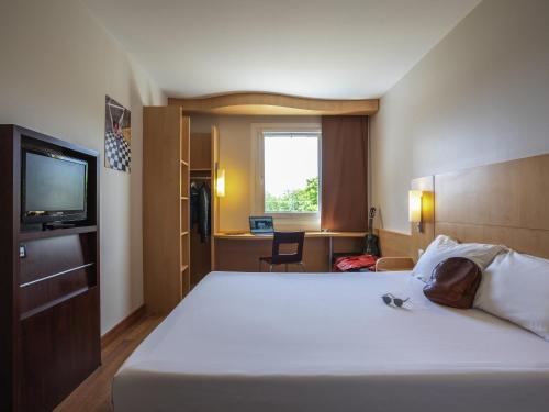 a hotel room with a bed and a television at Ibis Hotel Plzeň in Plzeň