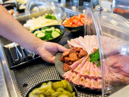 a person is reaching for a plate of food at Ibis Hotel Plzeň in Plzeň