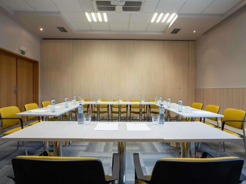 a conference room with white tables and yellow chairs at Ibis Hotel Plzeň in Plzeň