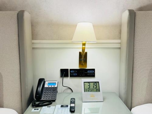a lamp on a table with a telephone and a phone at TAJ Executive Hotel F7 Islamabad in Islamabad