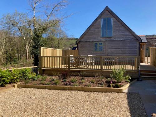 a house with a wooden deck and a garden at The Haybarn in Woolland