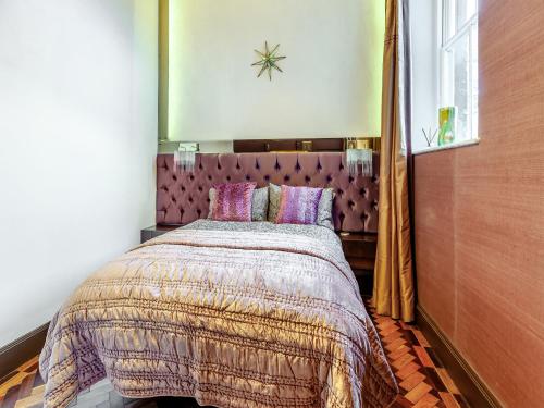 a bedroom with a large bed with a purple headboard at The Old School Room in Frome