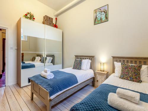 a bedroom with two beds and a mirror at The Old School Room in Frome