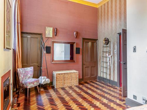 a room with a red wall with a chair and a mirror at The Old School Room in Frome