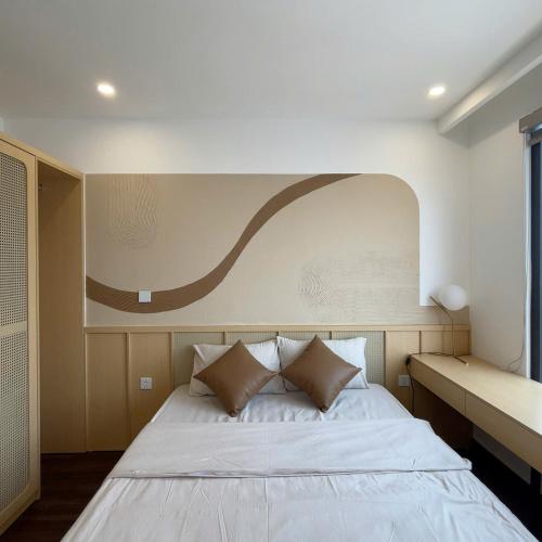 a bedroom with a bed with a painting on the wall at Hoàng Huy Commerce Võ Nguyên Giáp Mopius Apartment in Hai Phong