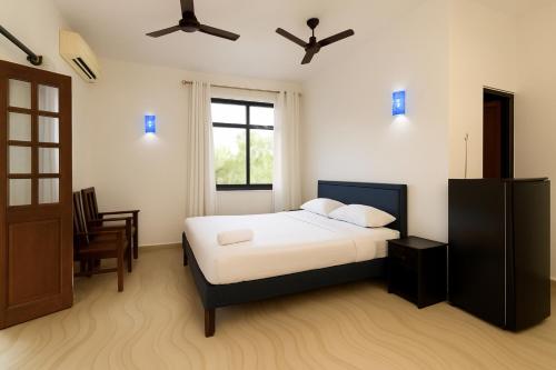 a bedroom with a bed with white sheets and a window at Sandeep Gurung Homes Stay in Calangute