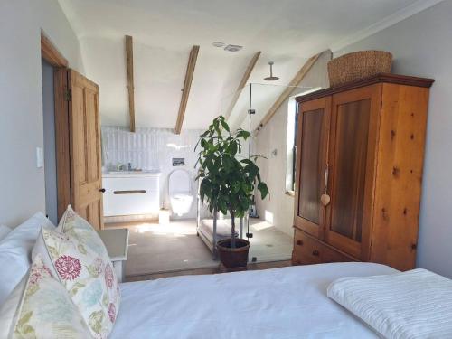 a bedroom with a bed and a cabinet and a plant at Foam House in Bloubergstrand