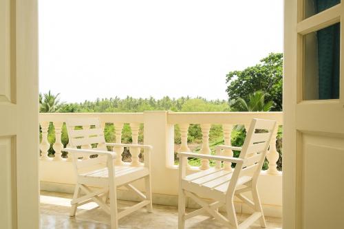 a balcony with two white chairs and a window at Sandeep Gurung Homes Stay in Calangute