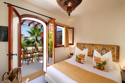 a bedroom with a bed and a balcony with a table at Le Calette Bay in Cefalù