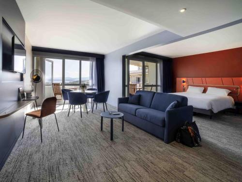 a hotel room with a blue couch and a bed at Mercure Thalasso & Spa Port Fréjus in Fréjus