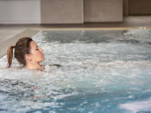 a young girl is swimming in a jacuzzi at Mercure Thalasso & Spa Port Fréjus in Fréjus
