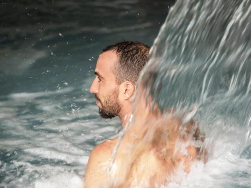 a man standing in the water under a waterfall at Mercure Thalasso & Spa Port Fréjus in Fréjus