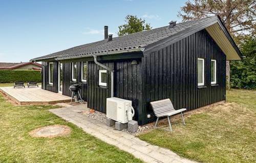 a black house with a bench in a yard at 2 Bedroom Awesome Home In Bogense in Bogense