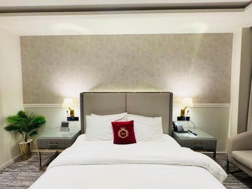 a bedroom with a white bed with a red pillow at TAJ Executive Hotel F7 Islamabad in Islamabad
