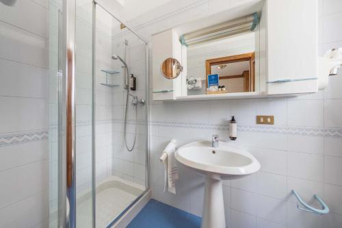 a white bathroom with a sink and a shower at Franceschi Park Hotel in Cortina dʼAmpezzo