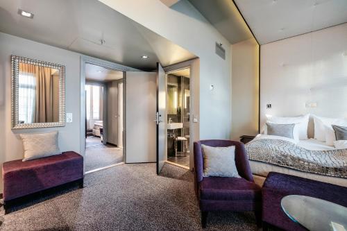 a bedroom with a bed and a chair and a mirror at Home Hotel Folketeateret in Oslo