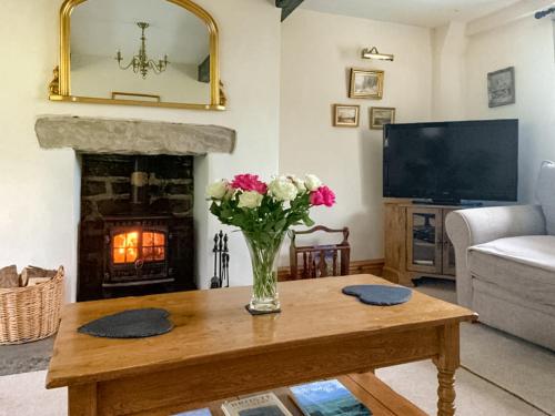 a living room with a vase of flowers on a table at Royds Hall Cottage in Keighley