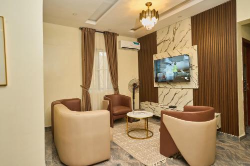 a living room with chairs and a tv on a wall at Shabi's Court in Lagos