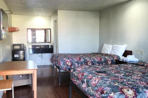 a small hotel room with two beds and a table at Deluxe Inn Motel By OYO Grand Prairie Interstate 30 in Grand Prairie