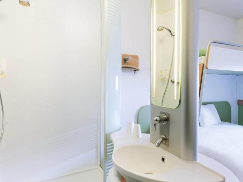 a bathroom with a sink and a mirror and a bed at ibis Budget Luxembourg Sud in Livange
