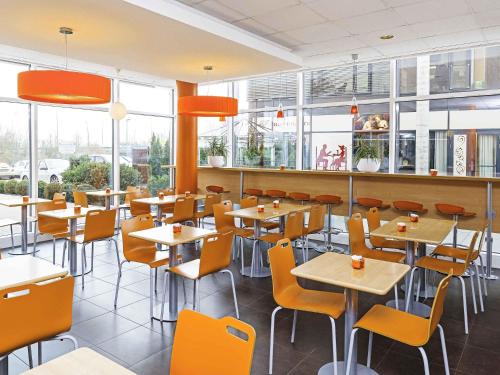 a restaurant with tables and chairs and windows at ibis Budget Luxembourg Sud in Livange
