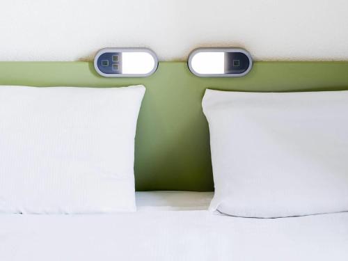 a bed with two monitors on top of it at ibis Budget Luxembourg Sud in Livange
