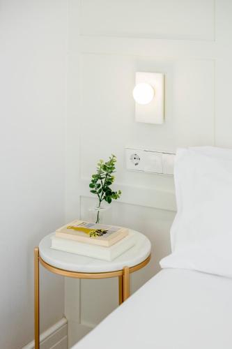 a small table with a book and a plant on it at Room Mate Cosmo - City Centre, Valencia in Valencia