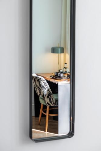 a mirror reflecting a desk with a chair and a lamp at Room Mate Cosmo - City Centre, Valencia in Valencia