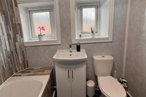 a bathroom with a sink and a toilet and two windows at Grantham House - Sleeps 6 - Pet friendly - Parking in Newcastle upon Tyne