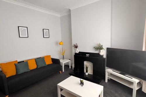 a living room with a black couch and a fireplace at Grantham House - Sleeps 6 - Pet friendly - Parking in Newcastle upon Tyne