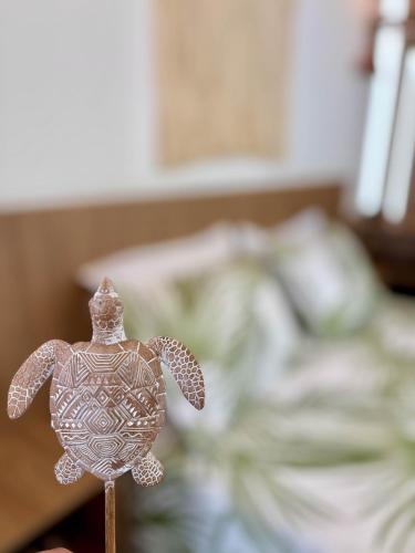 a small figurine of a sea turtle on a stick at Villa Naluri - Studio A001 no paraíso Japaratinga! in Japaratinga