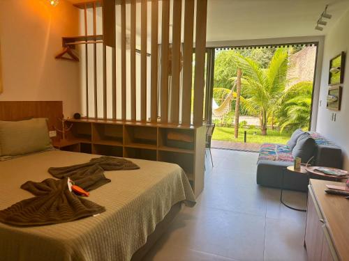 a bedroom with a bed and a couch and a window at Villa Naluri - Studio A001 no paraíso Japaratinga! in Japaratinga