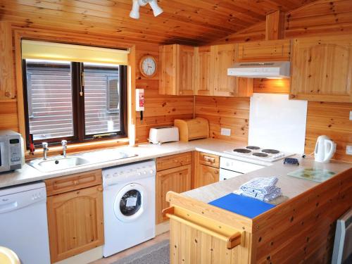 Una cocina con lavadora y secadora en una cabaña. en Glenmore Lodge, en Keswick