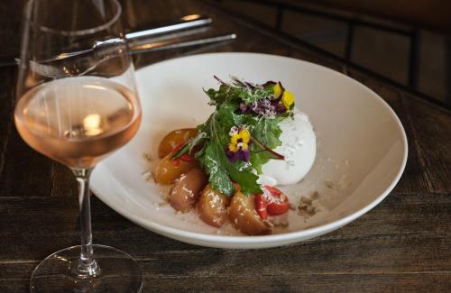 a white plate of food and a glass of wine at The Posthouse Berlin Potsdamer Platz- Leonardo Limited Edition in Berlin