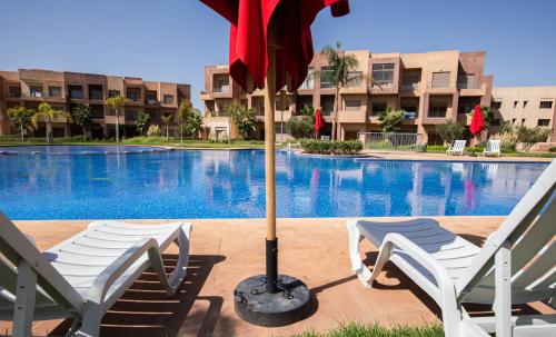 two chairs and an umbrella in front of a pool at confort et détente à Marrakech-Appartement 2 Chambres avec Piscine in Marrakech