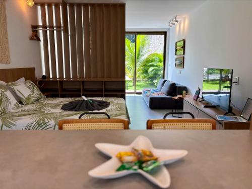 a room with a bed and a table with two plates of food at Villa Naluri - Studio A001 no paraíso Japaratinga! in Japaratinga