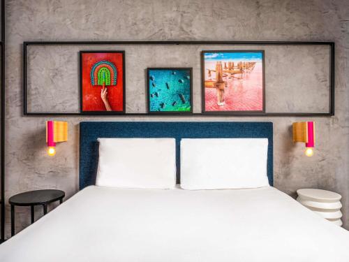 a bedroom with a white bed with three pictures on the wall at Ibis Styles Dakar in Dakar