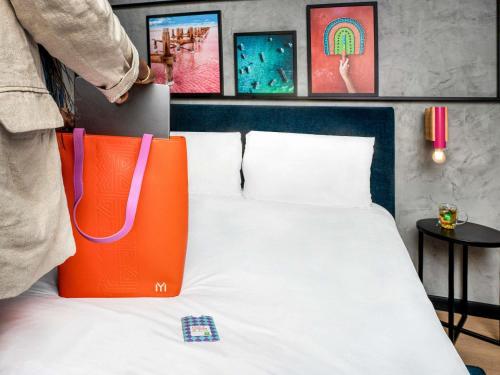 a bed with an orange and white bag on it at Ibis Styles Dakar in Dakar