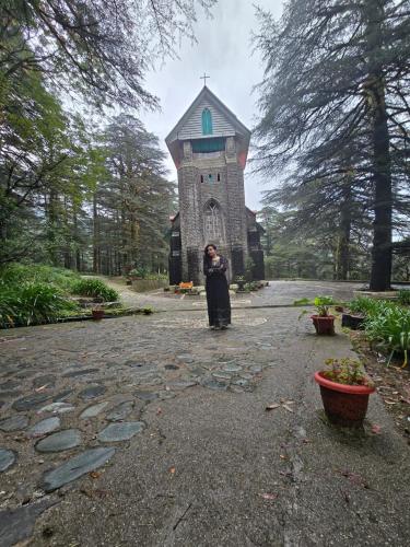 a woman standing in front of a building at Tranquil trails home stay naddi in Dharamshala
