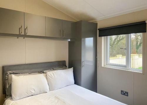 a bedroom with a bed with white pillows and a window at Arran Hills in Kilwinning